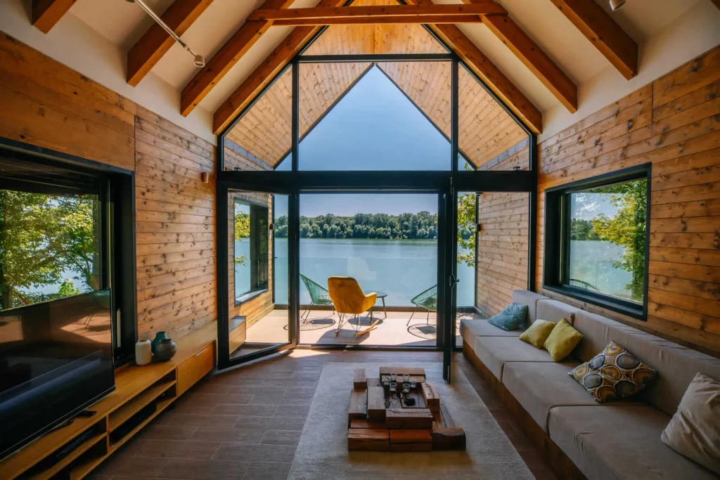 Imagem do ambiente interno de um chalé em frente ao lago mostra decoração em tons amadeirados do espaço para ilustrar matéria sobre como decorar um imóvel de veraneio