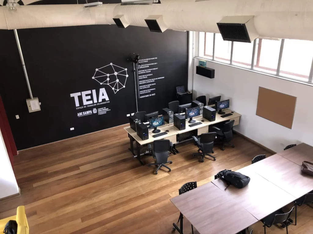 Imagem da parte interna de um dos escritórios do programa, com vista para os computadores e mesas, para ilustrar matéria sobre coworking gratuito em São Paulo