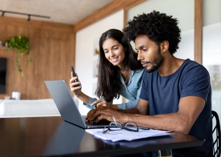 imagem que ilustra matéria sobre declarar imóvel quitado no IR 2025 mostra um casal sentado em frente ao computador