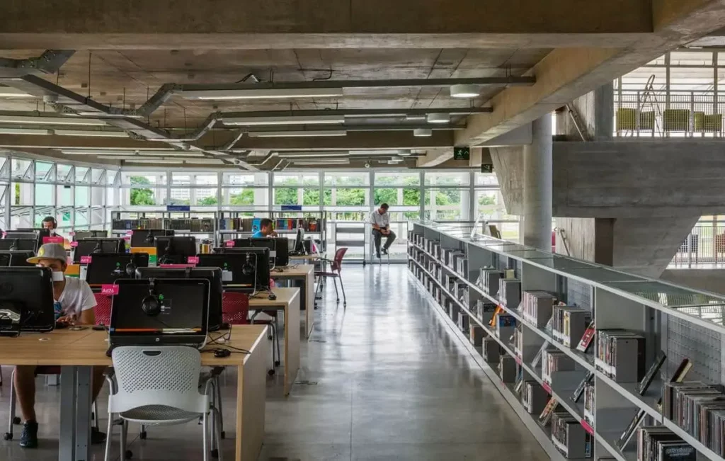 Imagem da parte interna do espaço de leitura, com mesas equipadas com computadores ao lado de estantes de livros para ilustrar matéria sobre os lugares gratuitos para trabalhar em SP
