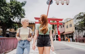 Imagem de duas amigas conversando enquanto caminham pela Liberdade, o bairro japonês em São Paulo