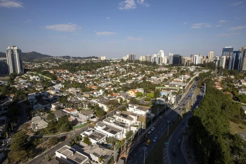 Imagem aérea de uma área residencial da cidade de Barueri mostra avenidas, casas, prédios e vegetação em um dia de céu azul