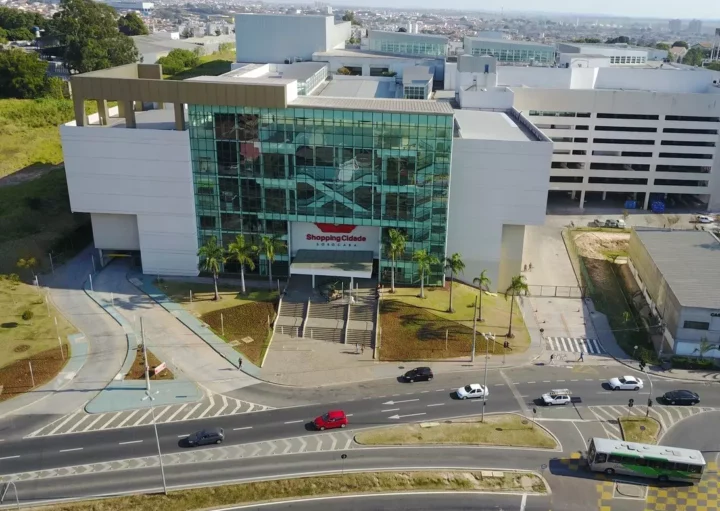 Vista aérea do Shopping Cidade Sorocaba, um dos principais shoppings em Sorocaba, com janelas de vidro, um estacionamento, palmeiras e carros circulando nas ruas próximas.