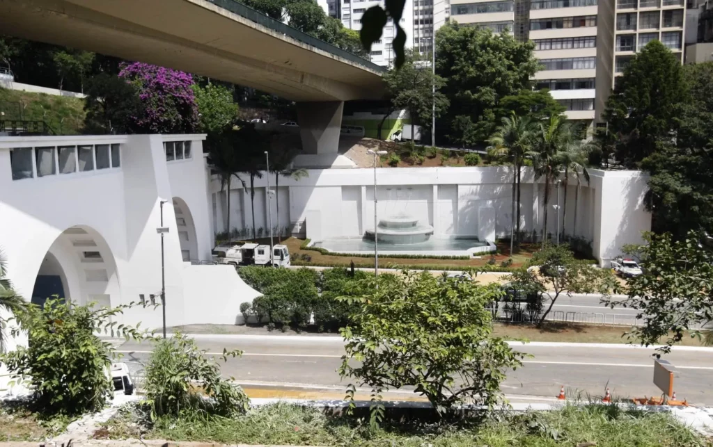 Imagem do Túnel 9 de julho mostra uma fonte circular na frente, ao lado da Avenida Nove de Julho. Vegetação e prédios ao fundo