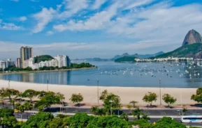 Imagem da vista aérea da Praia de Botafogo mostra mar, faixa de areia, vegetação e prédios ao redor