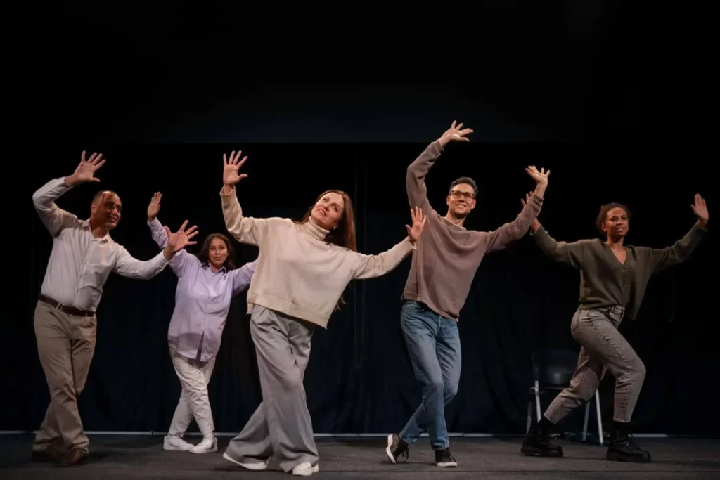 Imagem de cinco adultos se apresentando no palco de um teatro para ilustrar matéria sobre teatro em Belo Horizonte