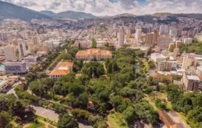 Imagem da vista aérea de Poços de Caldas mostra vegetação, prédios e montanhas ao fundo para ilustrar matéria sobre as cidades mais baratas para morar em Minas Gerais