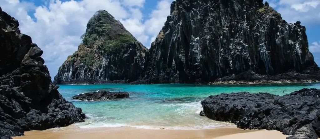 Imagem de praia e estruturas rochosas no Parque Nacional de Fernando de Noronha, em Pernambuco
